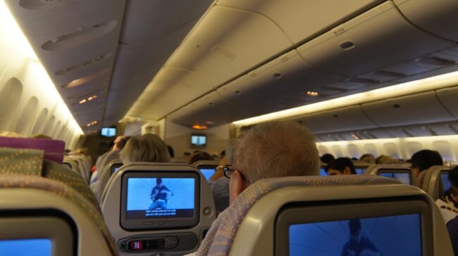 Cabina de avión con pantallas de entretenimiento individual en los asientos.