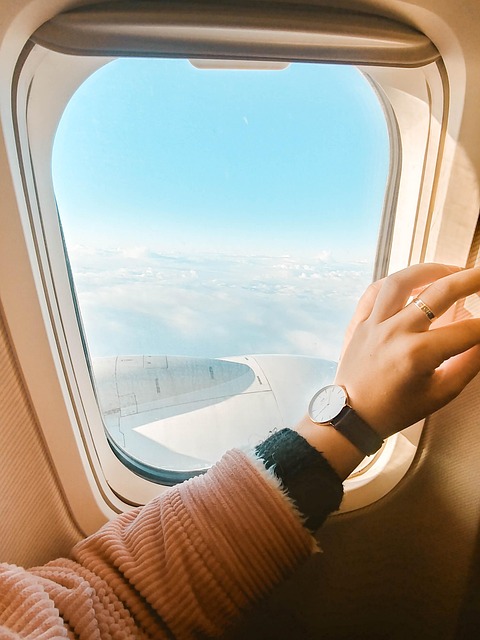 Brazo de mujer sobre la ventanilla del avión con el reloj en su muñena.