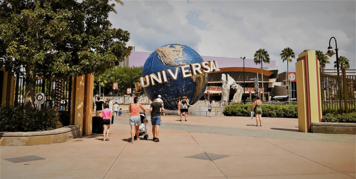 Visitantes caminando hacia el icónico globo de Universal Studios en la entrada principal del parque en Orlando.