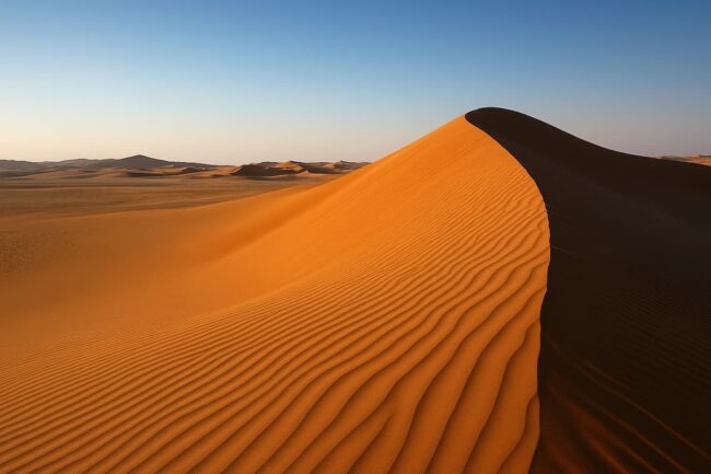 Dunas del desierto de Qatar iluminadas por el sol al atardecer.