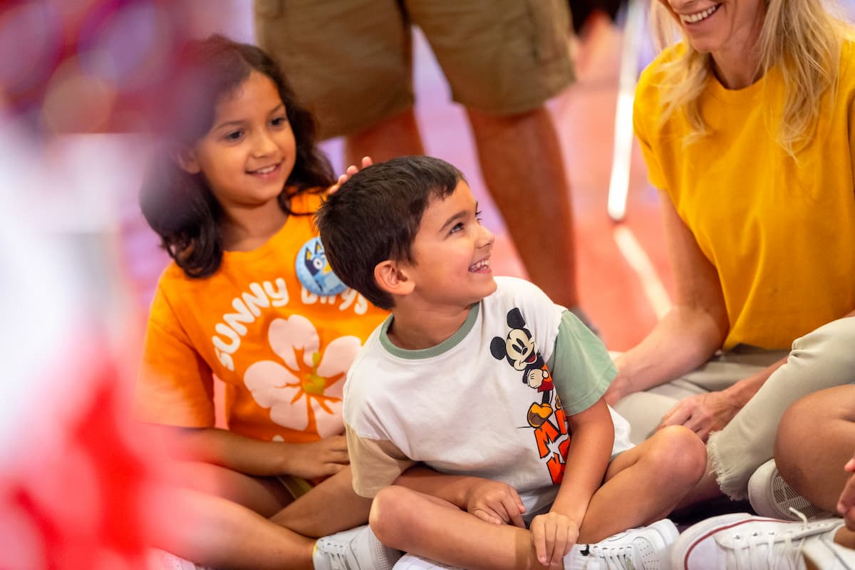 Niños sonrientes participando en una actividad en Disney, acompañados por adultos.