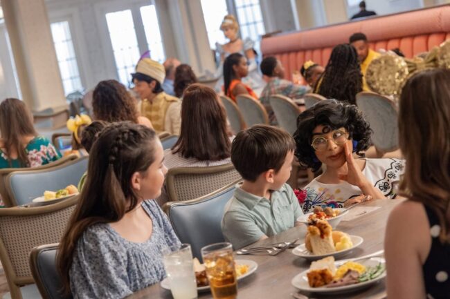 Familias compartiendo una comida en un restaurante de Disney, en un ambiente inclusivo y acogedor.