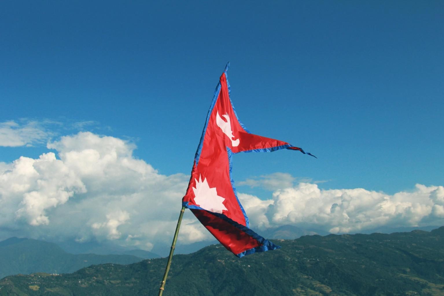 Bandera de Nepal ondeando con el Himalaya de fondo