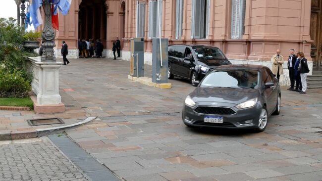 Vehículos ejecutivos frente a un edificio histórico en Buenos Aires durante un evento oficial.