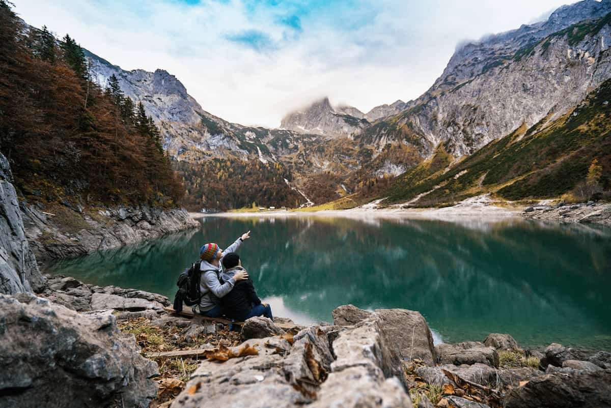 Pareja contemplando un lago entre montañas, disfrutando un viaje planificado con ayuda de la inteligencia artificial para optimizar gastos y experiencias.