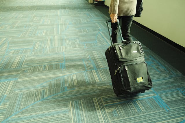 Persona caminando por el aeropuerto con una maleta de mano