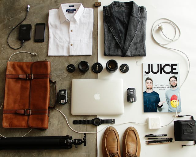 Artículos organizados para viaje de trabajo: laptop, cámara, ropa y accesorios
