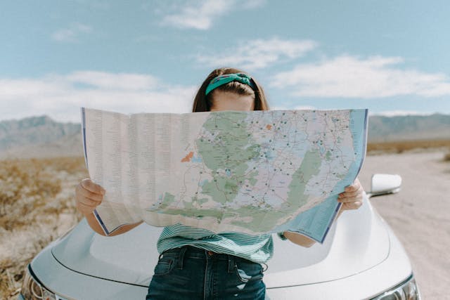 Viajera mirando un mapa durante un road trip, planificando su ruta con ayuda de la inteligencia artificial para ahorrar dinero en el viaje.