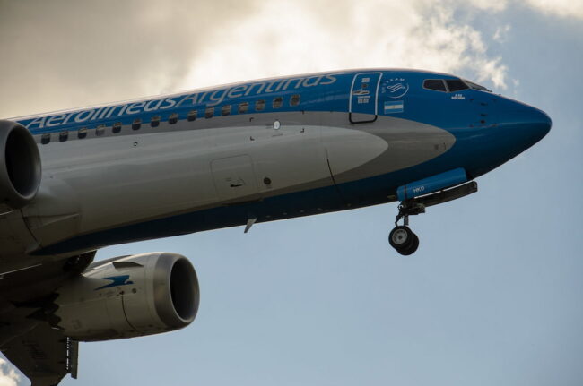 Avión de Aerolíneas Argentinas despegando, con detalle del fuselaje y motor.
