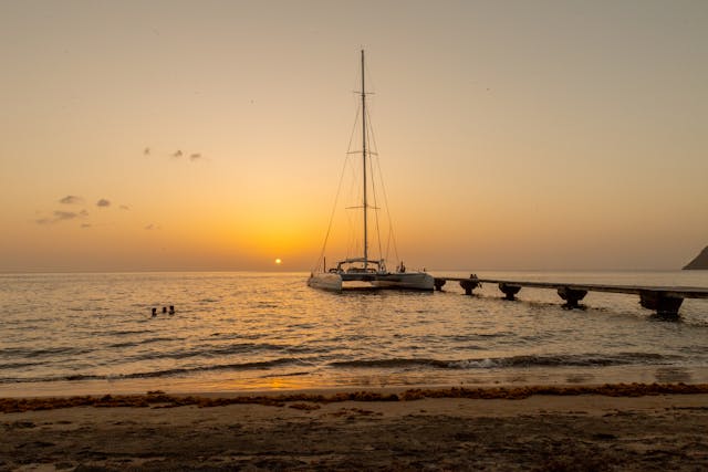 Atardecer con velero y muelle en una playa tropical del Caribe.
