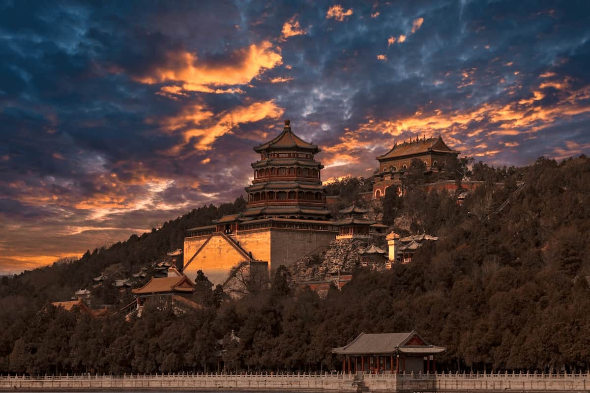 Templo antiguo en China iluminado por el atardecer, rodeado de montañas y arquitectura tradicional.