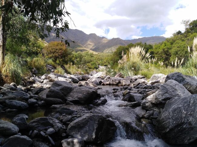 Arroyo de montaña en Merlo, San Luis, con rocas, vegetación nativa y sierras al fondo