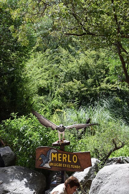 Cartel de bienvenida de Merlo, San Luis, rodeado de vegetación y naturaleza serrana