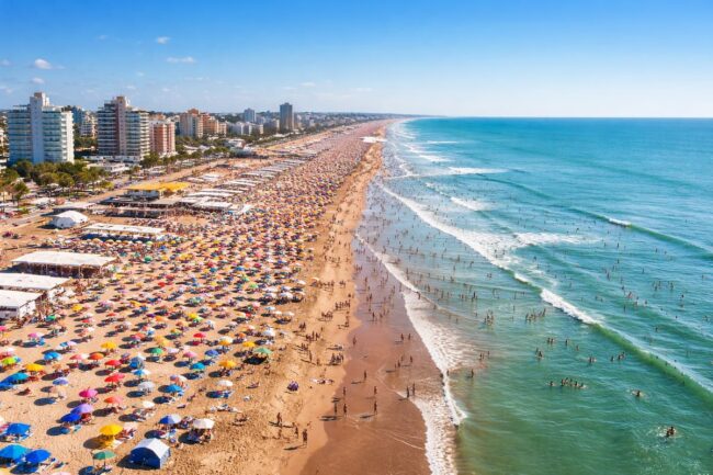 Playa de la costa argentina llena de sombrillas y turistas junto al mar en temporada de verano