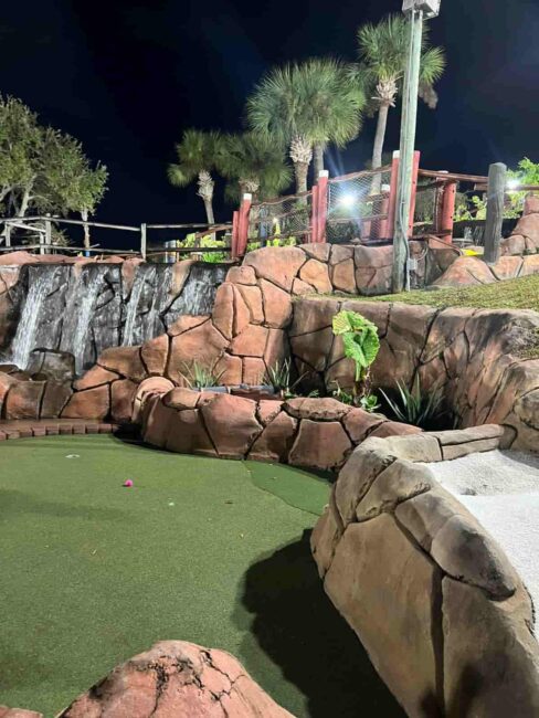 Campo de mini golf nocturno en Pirate’s Island Golf Orlando con cascadas y ambientación tropical