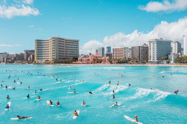 Playa de Cancún con surfistas y hoteles frente al mar, uno de los mejores destinos baratos para viajar desde Texas en 2026.