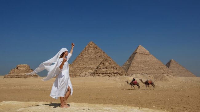 Mujer en las pirámides de Egipto con dos camellos de fondo