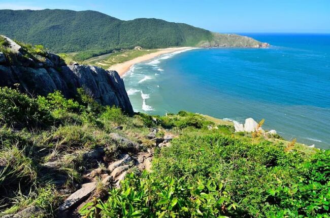 Playa natural en Florianópolis con acantilados y mar azul, ideal para hoteles familiares frente al mar en 2026