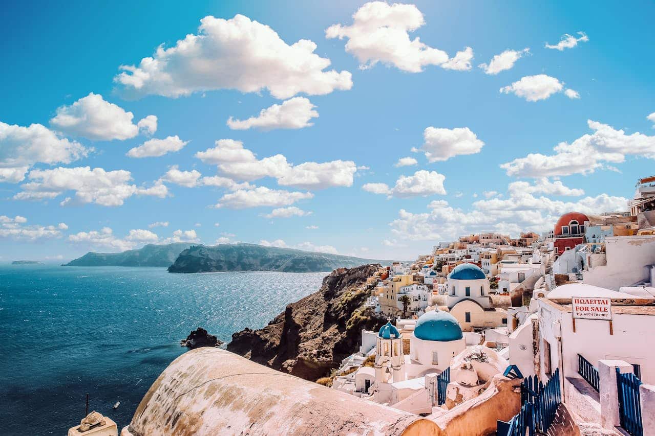 Vista del pueblo de Oia en Santorini con casas blancas y cúpulas azules frente al mar Egeo