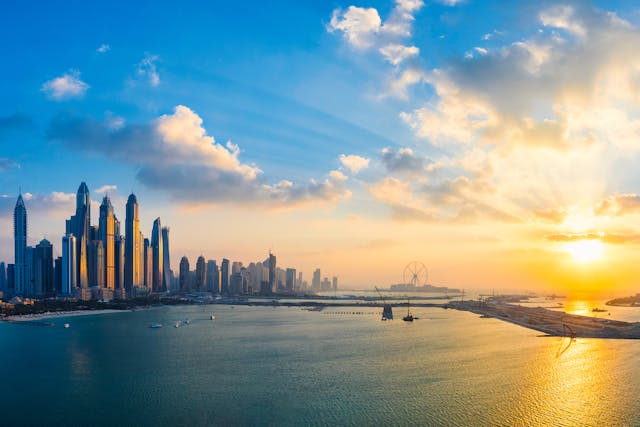 Skyline moderno de Dubái al atardecer junto al mar, ejemplo de su perfil futurista frente a Abu Dhabi