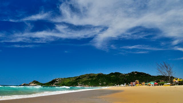 Playa de Brasil con arena dorada, mar turquesa y cerros al fondo ideal para viajar desde Argentina