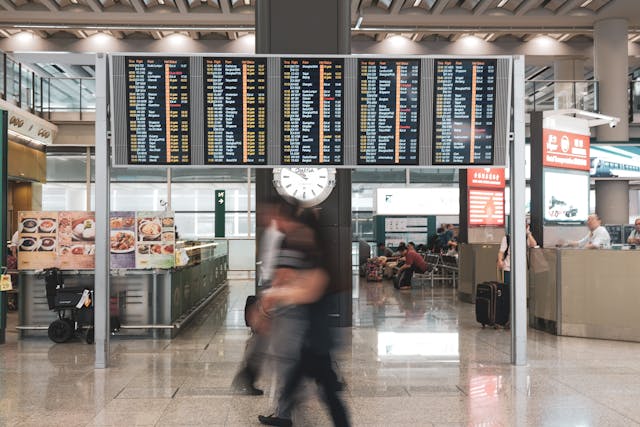 Pantalla de vuelos y pasajeros caminando en terminal de uno de los aeropuertos con más tráfico del mundo en 2025