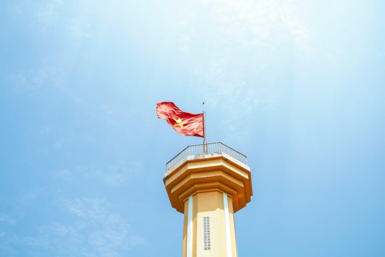 Bandera de Vietnam ondeando en torre mirador bajo cielo despejado.