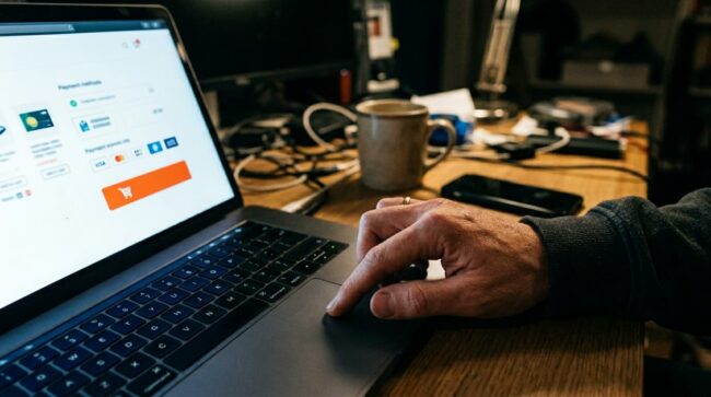 persona comprando online ofertas del hot sale en laptop con tarjeta y carrito de compra