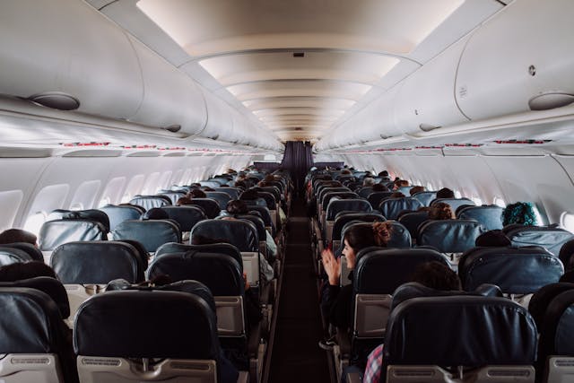 Interior de avión comercial con filas de asientos ocupados, típico de vuelos low cost con cabina de alta densidad.