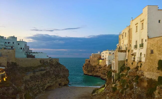 Casas blancas sobre acantilados en Polignano a Mare junto a una cala frente al mar Adriático.