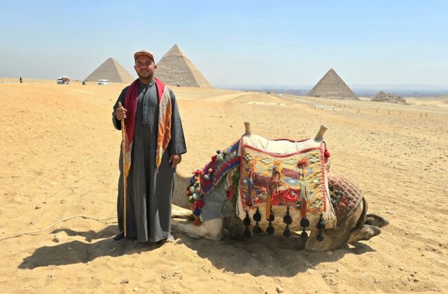 Gu&iacute;a local y camello frente a las pir&aacute;mides en Egipto