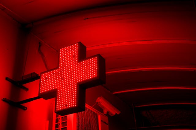 Símbolo luminoso de cruz médica roja, imagen conceptual sobre alerta sanitaria y riesgos de salud en viajes