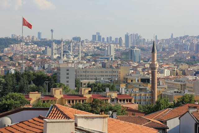 Vista panorámica de Ankara con mezquitas, edificios modernos y la bandera de Turquía.