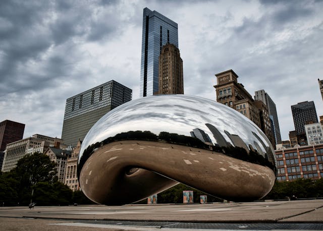 Cloud Gate en Millennium Park, una de las zonas turísticas más visitadas de Chicago, con rascacielos y cielo nublado.