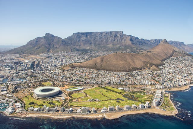 Ciudad del Cabo entre los destinos turísticos que crecen este año Vista aérea de Ciudad del Cabo con la Montaña de la Mesa, el estadio y la costa, uno de los destinos que gana atractivo turístico por su mezcla de naturaleza, vida urbana y paisajes únicos.