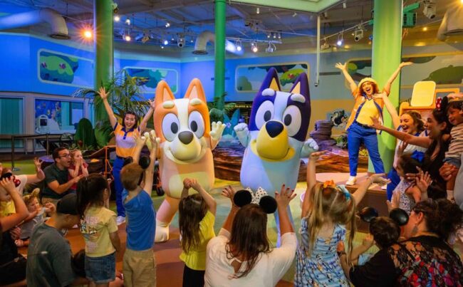 Familias con niños disfrutan una experiencia con personajes de Bluey en Walt Disney World durante la temporada de verano.