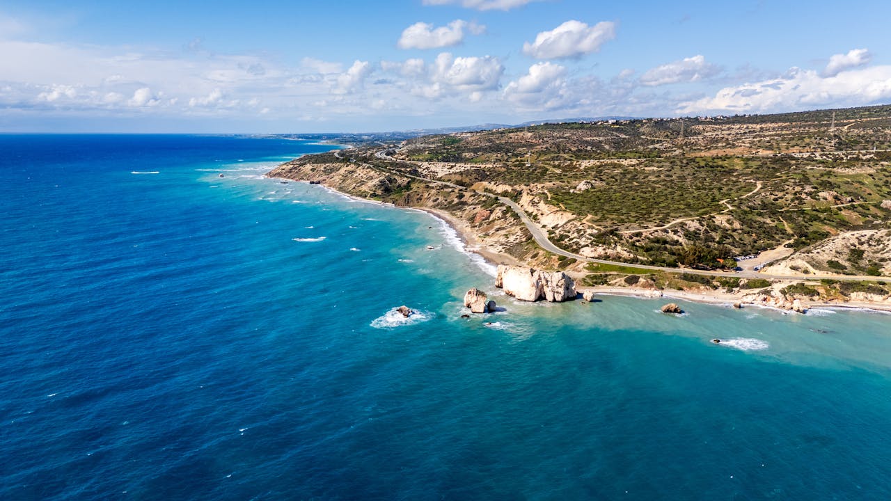 Vista aérea de la costa de Chipre sobre el mar Mediterráneo, con acantilados, playas y aguas turquesas.