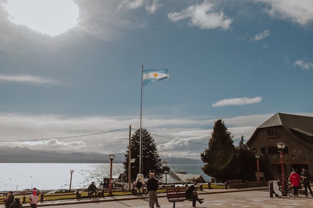 Bandera argentina frente a un paisaje de lago y montaña, como referencia a destinos nacionales con promociones durante el Hot Sale de viajes.