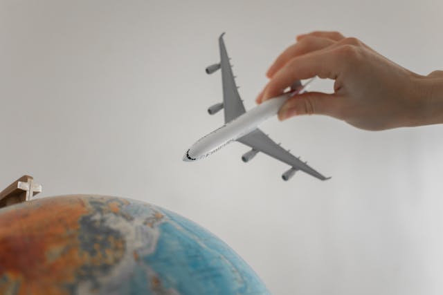 Mano sosteniendo un avión sobre un globo terráqueo como referencia a ofertas de vuelos y paquetes durante el Hot Sale de viajes.