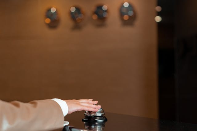 Mano tocando el timbre de recepción de un hotel, una imagen que representa el check-in y la organización necesaria para hacer hotel hopping durante un viaje.
