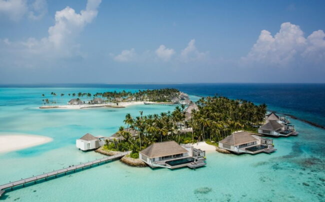 Resort de lujo en Maldivas con villas sobre el agua, palmeras y laguna turquesa, una imagen que representa los hoteles más caros del mundo en 2026 y las experiencias exclusivas de lujo extremo.