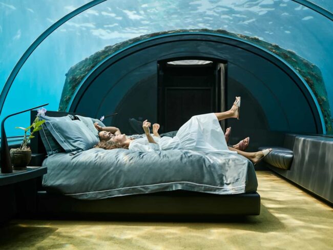 Interior de The Muraka en Maldivas, una suite submarina de lujo extremo con dormitorio rodeado por vistas al océano, ideal para ilustrar los hoteles más caros del mundo en 2026.