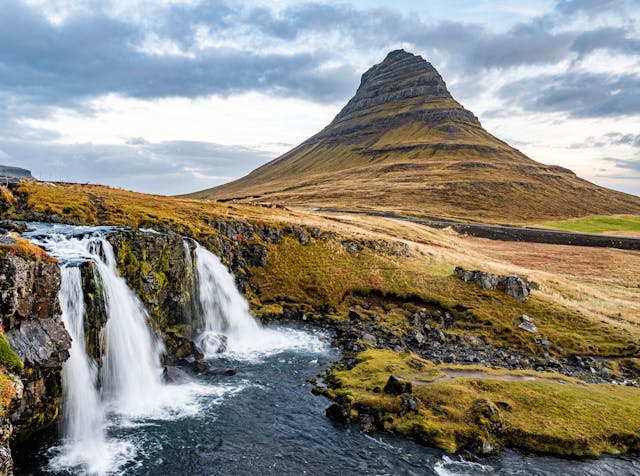 Paisaje natural de Islandia con montaña y cascada, uno de los destinos que más crece en turismo por sus rutas escénicas, naturaleza extrema y experiencias al aire libre.
