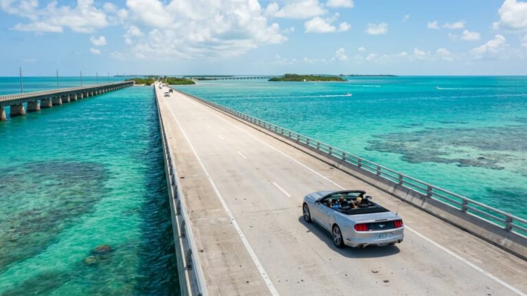 Auto recorriendo un puente sobre aguas turquesas en la ruta de Miami a Key West, una imagen que muestra el viaje por la Overseas Highway y la distancia entre ambos destinos de Florida.
