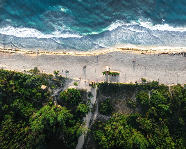 Vista aérea de una playa del Caribe mexicano con mar turquesa, arena clara y vegetación en la Riviera Maya.