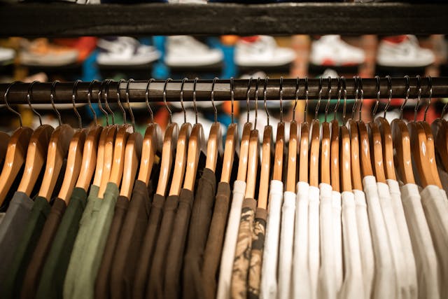 Ropa colgada en una tienda de Estados Unidos con prendas y zapatillas al fondo