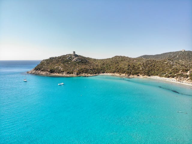 Vista de Cerdeña, en Italia, con una cala de aguas turquesas y costa rocosa mediterránea.
