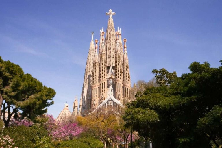 Vista de la Sagrada Familia en Barcelona rodeada de &aacute;rboles, una de las visitas principales para calcular el presupuesto del viaje.