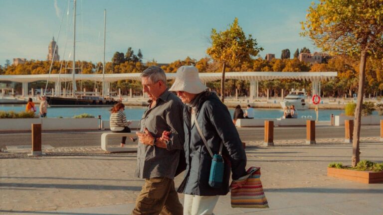 Pareja de adultos mayores caminando por un paseo costero, imagen asociada a destinos accesibles para jubilados en 2026.