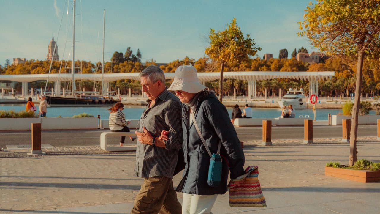 Pareja de adultos mayores caminando por un paseo costero, imagen asociada a destinos accesibles para jubilados en 2026.
